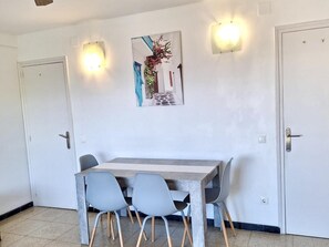 Ein Essbereich mit einem Tisch, vier Stühlen, zwei Wandleuchten und einem gerahmten Bild an der Wand.