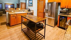 A modern kitchen with wooden cabinets, a stainless steel refrigerator, a built-in oven, and a granite countertop.
