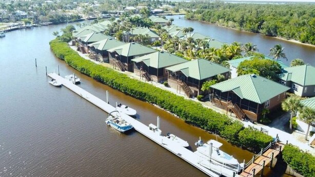 A waterfront hotel with multiple buildings, a dock with boats, and a river.