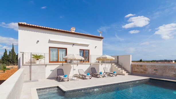 Una villa moderna con piscina, area salotto esterna e vista sul paesaggio.