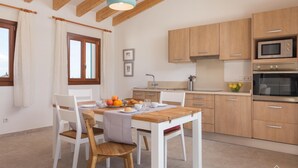 Una cucina moderna con mobili in legno, un tavolo da pranzo con sedie e una lampada a sospensione.