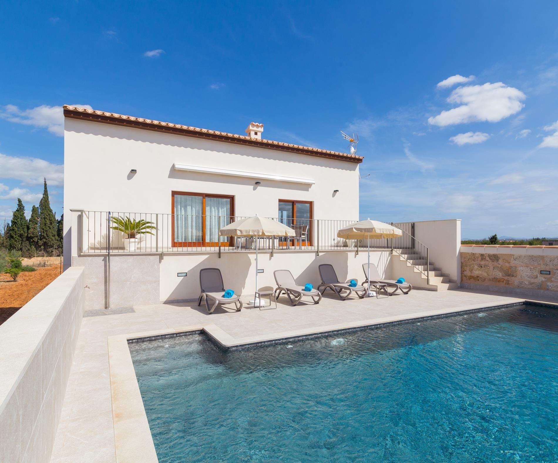 A modern villa with a swimming pool, outdoor seating, and a view of the landscape.