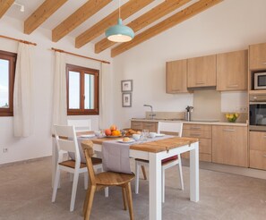 Une cuisine moderne avec des meubles de rangement en bois, une table à manger avec des chaises et un luminaire suspendu.