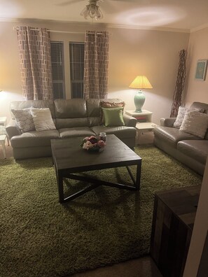 Un salon comprenant un canapé, une table basse, une lampe et un vase décoratif.