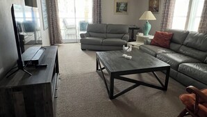 Una sala de estar con sofá, mesa de centro, televisor y ventilador de techo.