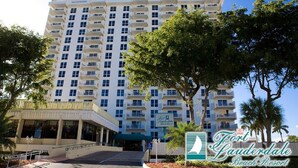 Un hôtel à plusieurs étages doté d’une entrée centrale, de balcons et d’une enseigne indiquant qu’il s’agit du Fort Lauderdale Beach Resort.