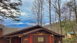 A rustic cabin with a wooden exterior, a porch, and a small seating area. - Pappy’s Hideaway (Gatlinburg)