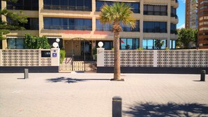 A building with a gated entrance, a palm tree, and a patterned fence.