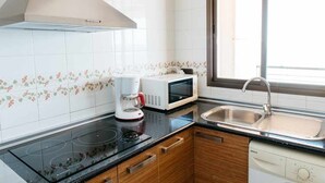 A kitchen with a stove, microwave, coffee maker, and sink.
