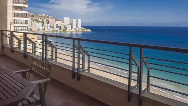 A balcony with a view of the ocean and a cityscape.