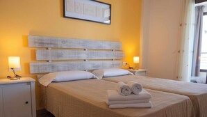 A hotel room with two beds, a marble floor, and a framed artwork above the beds.