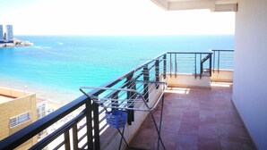 Ein Balkon mit Meerblick, einem Metallgeländer und einem blauen Korb.