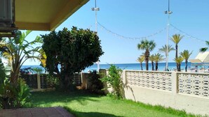 Un'area patio con vista sulla spiaggia, palme e luci decorative.