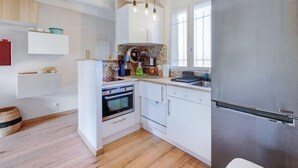 Une cuisine moderne avec des armoires blanches, un réfrigérateur en acier inoxydable et un four encastré.