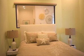 Comfortable bed with a beige headboard and matching bedspread, accompanied by two bedside tables with lamps and telephones.