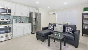 A modern kitchen with white cabinets, stainless steel appliances, and a tiled backsplash.