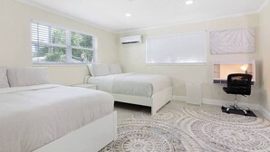 A bedroom with two beds, a desk, a chair, and a patterned rug.
