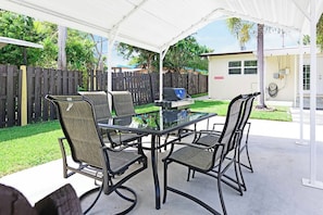 An outdoor patio with a glass table and four chairs, surrounded by a white canopy. - Private Guest suite with a beautiful view of the new hard rock hotel and casino (Fort Lauderdale)