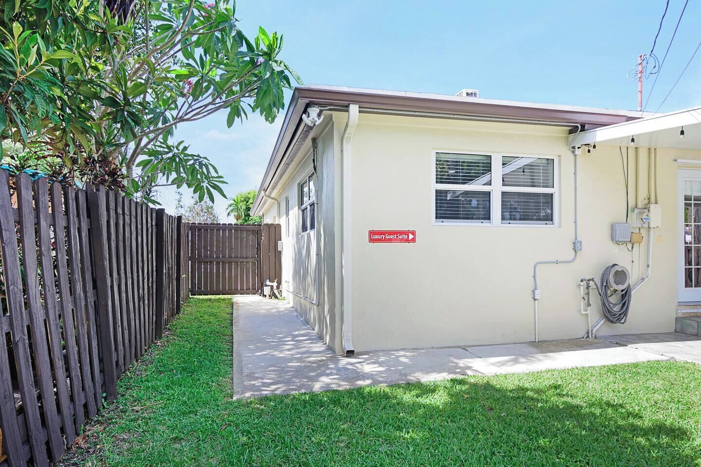 A single-story building with a 'Luxury Guest Suite' sign, a fenced yard, and a well-maintained lawn.