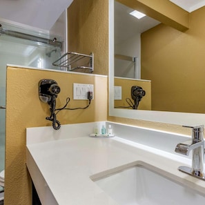 A bathroom with a white sink, a large mirror, and two hair dryers mounted on the wall. - Quality Inn and Suites Pawleys Island SC (Pawleys Island)