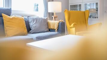 Ett vardagsrum med en soffa, en gul fåtölj och en lampa.