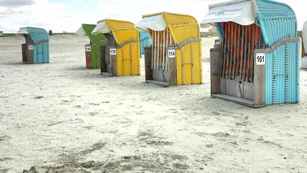 Beach huts numbered 157, 140, 178, 114, and 161 with a sandy beach and cloudy sky in the background.