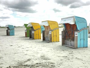 Bungalôs de praia numerados 157, 140, 178, 114 e 161, com uma praia de areia e um céu nublado ao fundo.