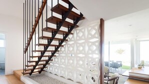 A modern staircase with wooden steps and black railings, leading to a landing with a white decorative partition.
