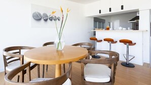 A modern kitchen with a central island, bar stools, and a dining table with chairs.