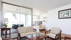 A modern living room with a sofa set, a coffee table, and a dining area with chairs and a table.