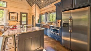 A modern kitchen with a large island, stainless steel appliances, and a wooden ceiling.