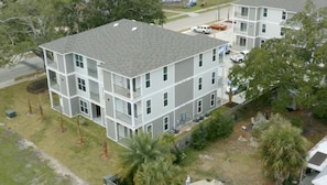 Stunning multi-story building with balconies and a flat roof design, set amidst a lush lawn and palm trees.