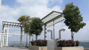 An outdoor terrace with a pergola, trees, and a view of a distant building. - GT Home Cascades Residency (Petaling Jaya)