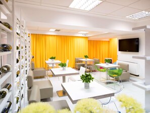 A modern hotel room with white furniture, a yellow curtain, and a TV on the wall. - Ibis Styles Skopje (Skopje)