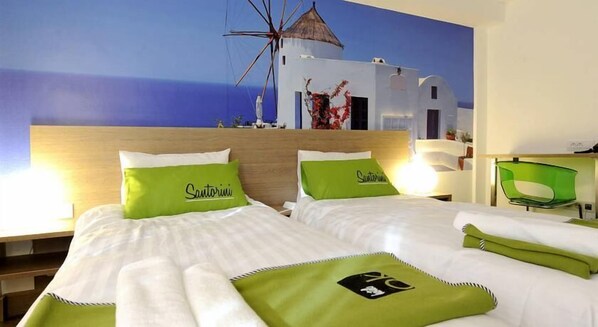 A hotel room with two beds, each with green and white bedding, and a mural of a white building against a blue sky. - Ibis Styles Skopje (Skopje)
