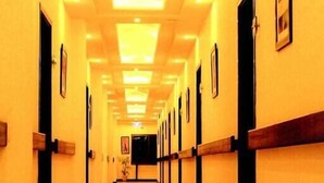 A long, well-lit hallway with doors on both sides, leading to rooms. - Hotel One DG Khan (Dera Ghazi Khan)