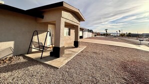 Um edifício com fachada de concreto, uma porta e uma pequena área externa com uma escada de metal.