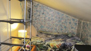 A dormitory room with bunk beds, a shelf with a lamp, and a wall with a floral pattern. - Downtown Craig (Craig)