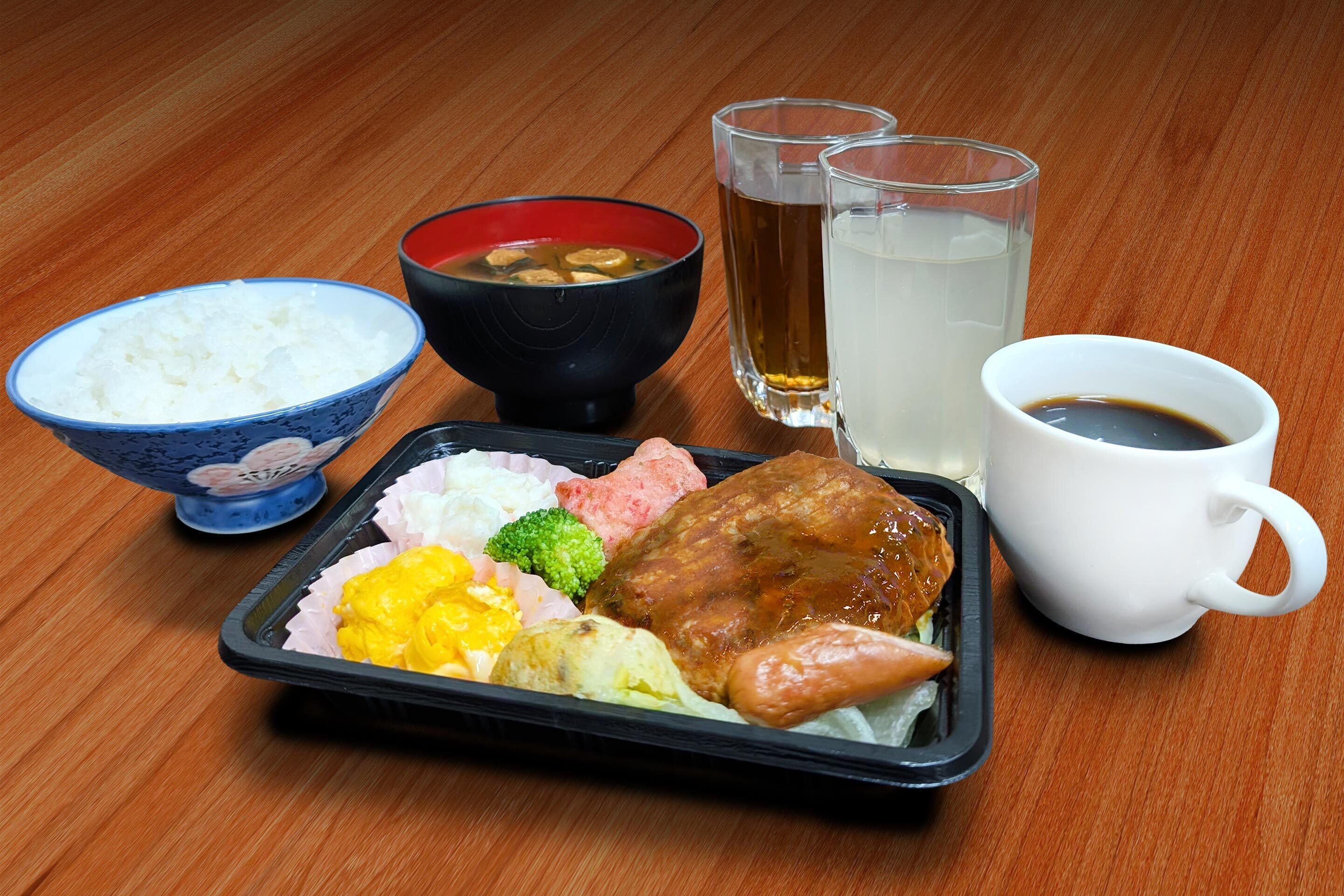 A meal with rice, soup, and drinks on a wooden table.