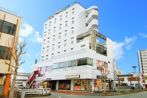 Un hôtel à plusieurs étages doté d’une architecture moderne, avec une entrée imposante, un escalier et un grand panneau indicateur.