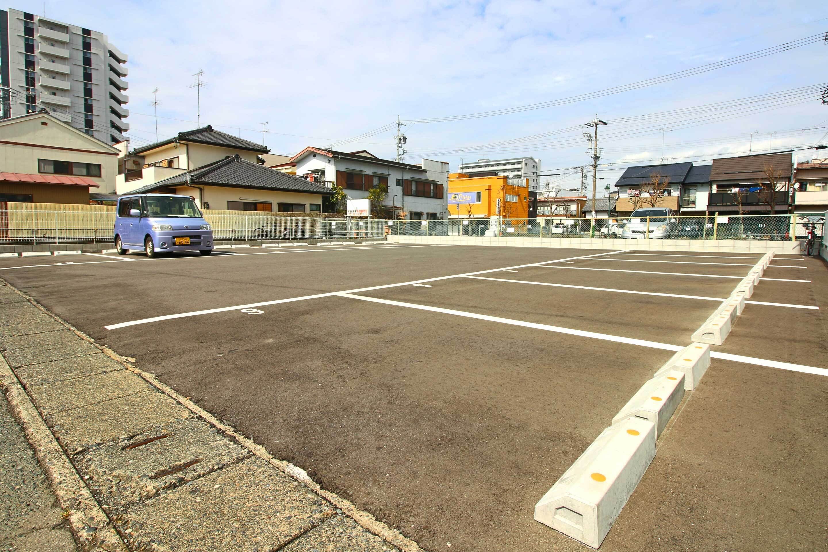 Un estacionamiento con espacios delimitados y una furgoneta azul estacionada en uno de ellos.
