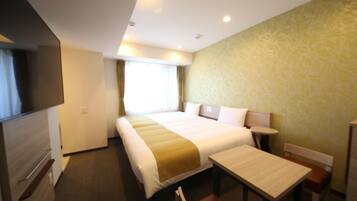 A hotel room with a large bed, a desk, and a chair. There is a window with curtains and a television on the left side.