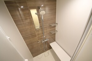 Une salle de bain moderne avec une douche, un miroir et des toilettes.