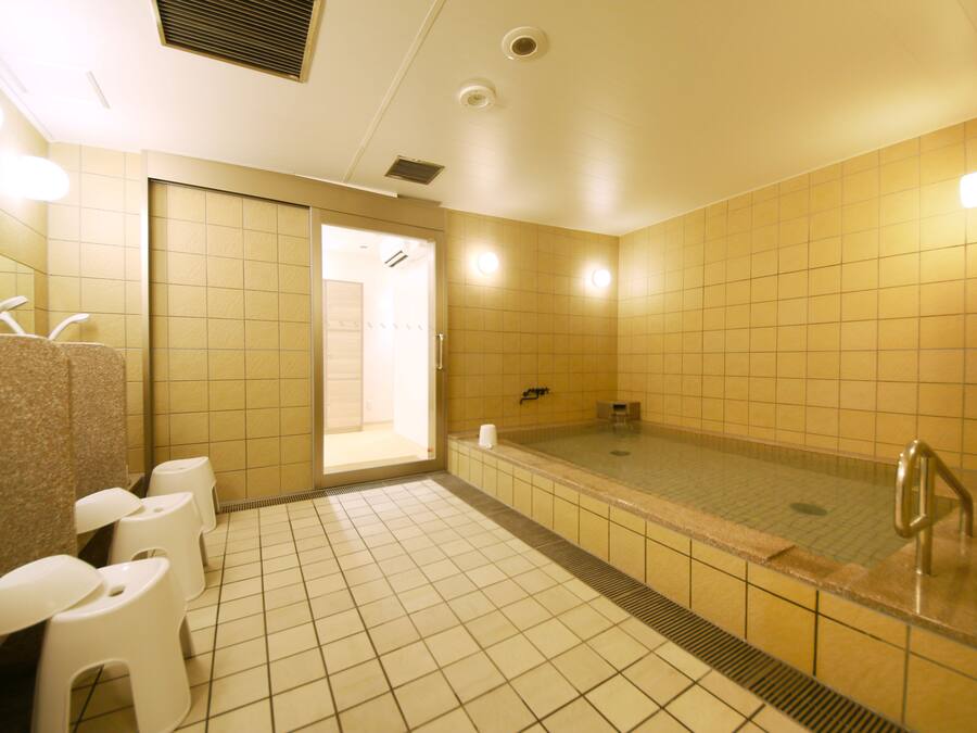 Een openbaar toilet met meerdere toiletten, een wastafel en een groot bad.