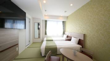 A hotel room with two beds, a dining table, a chair, a television, and a window with curtains.