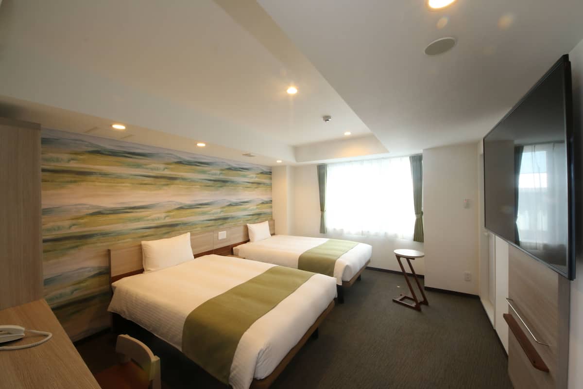 A hotel room with two beds, a desk, a chair, a television, and a painting on the wall.