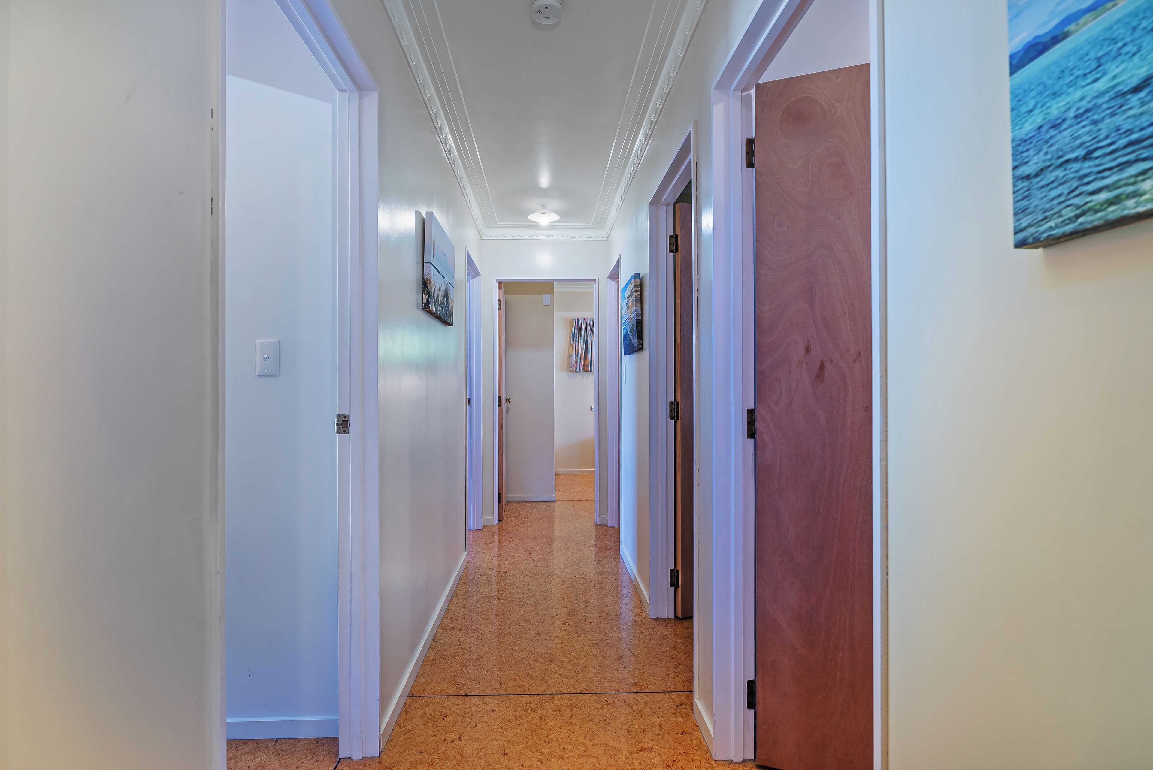 A hallway with white walls, wooden doors, and a tiled floor.