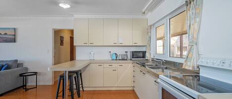 Una cocina compacta con una isla central, microondas y estufa.