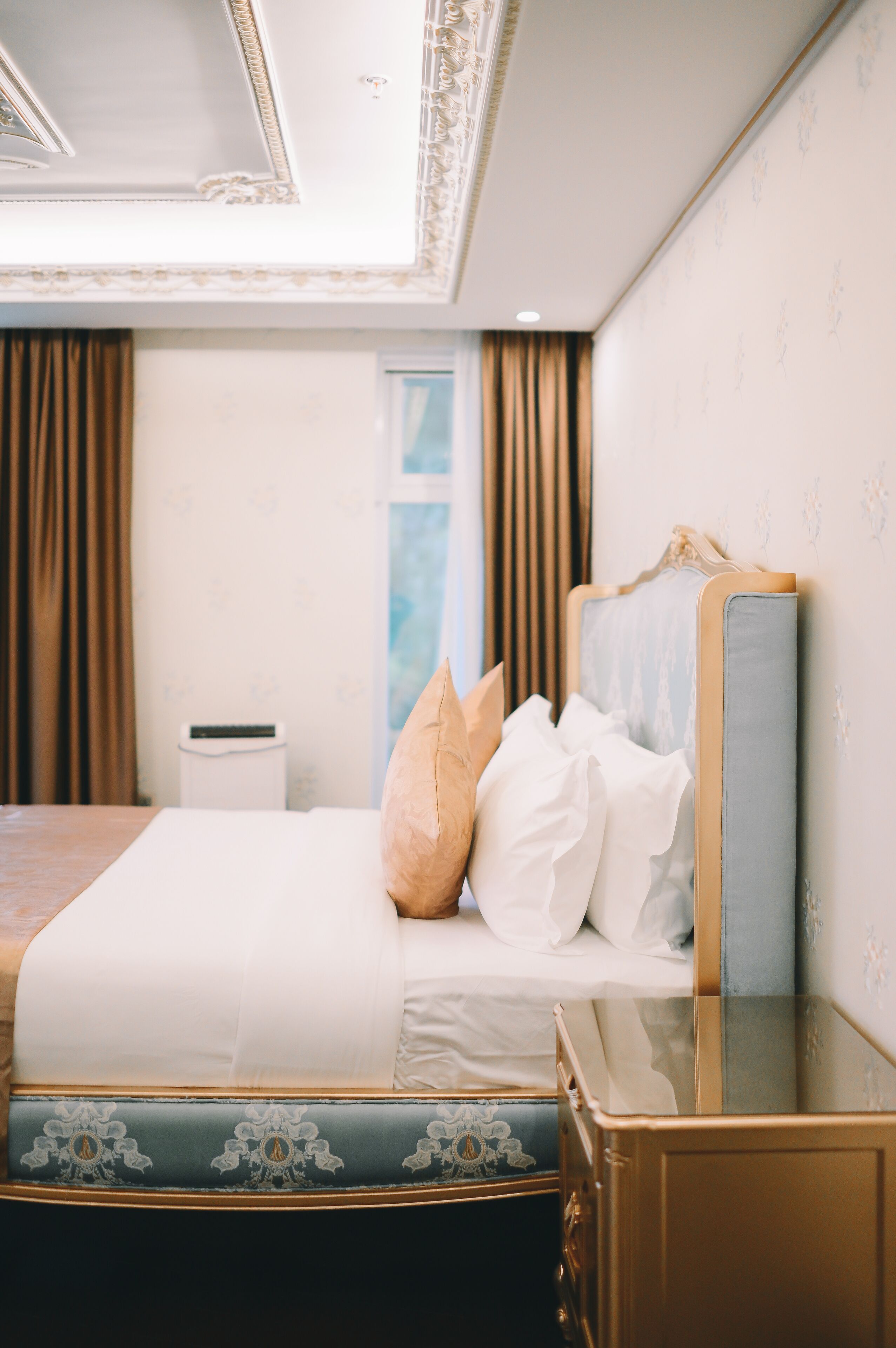 Ein Hotelzimmer mit einem großen Bett, einem Nachttisch, einem Spiegel und einem Fenster mit Vorhängen.