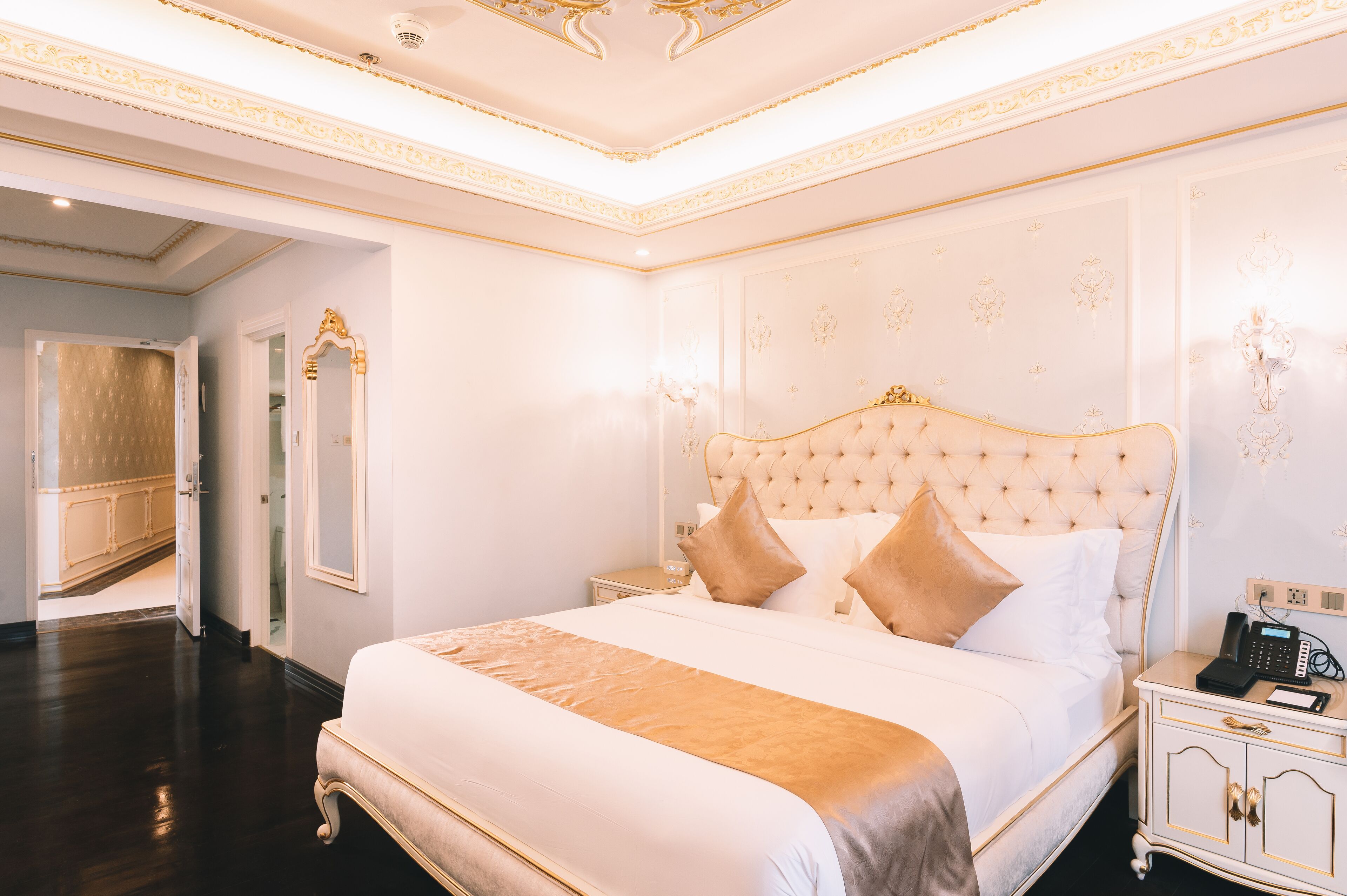 Une chambre à coucher luxueuse, dotée d’un grand lit, d’une table de chevet et d’un téléphone.